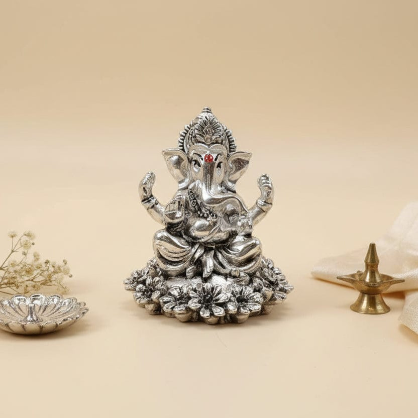 Silver Ganesha statue on a beige background with decorative elements.