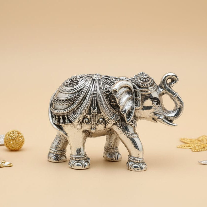 Decorative silver elephant figurine with gold jewelry on a beige background, featuring the brand 'Kanuveeda'.